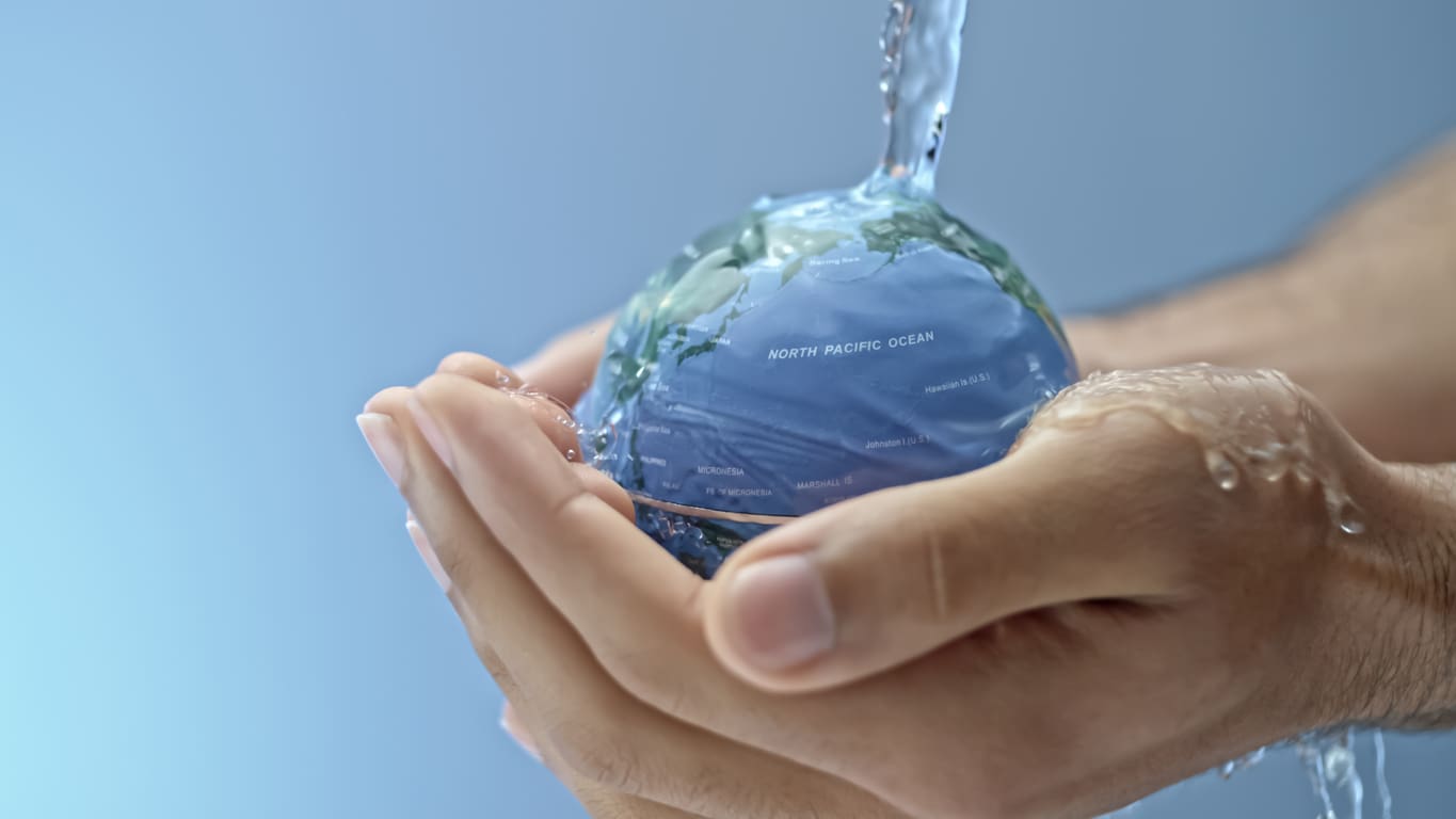 Hand Holding Globe Under Running Water